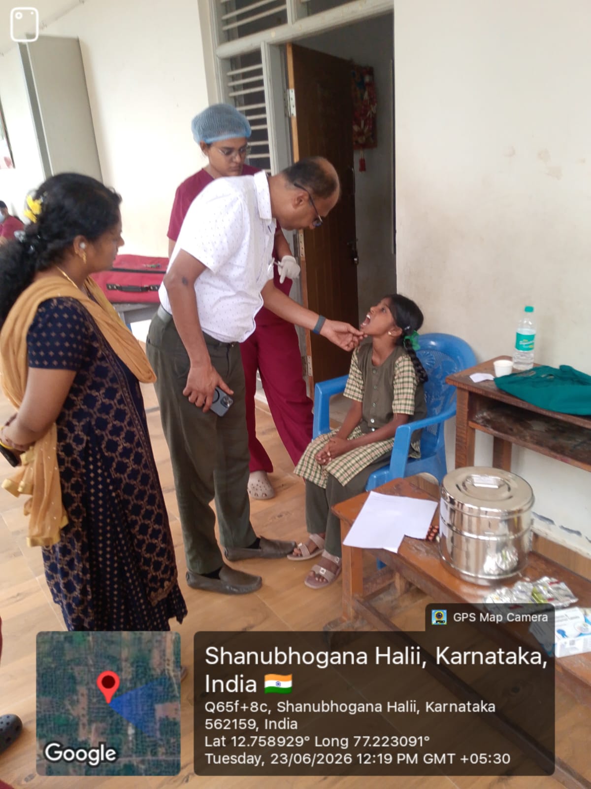 Dentist examining a female student's teeth, assisted by a team member